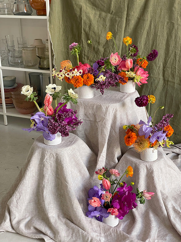Colorful floral arrangements in white vases on fabric