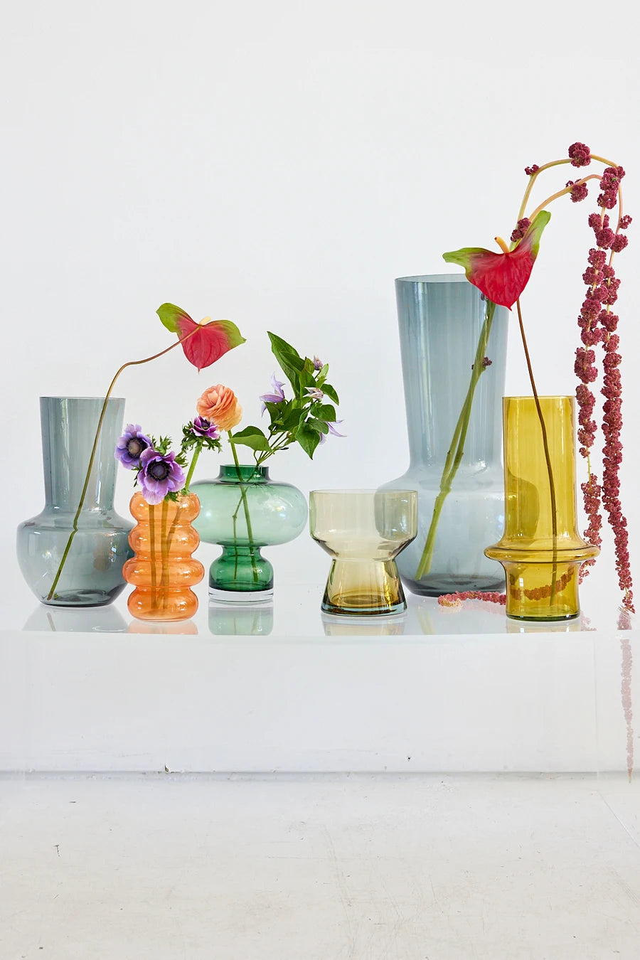 Glass vases with florals on white display shelf